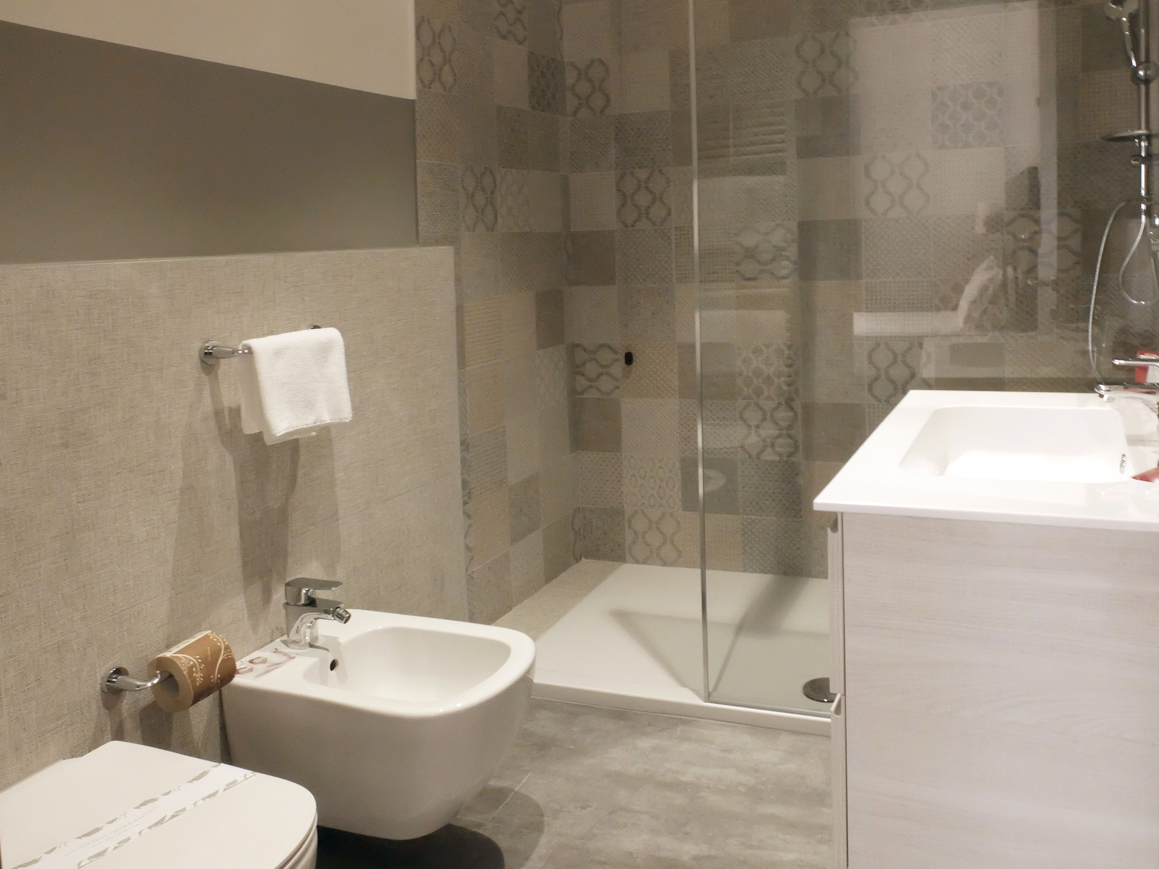 A modern bathroom with a bidet, a glass shower enclosure, and a white sink.