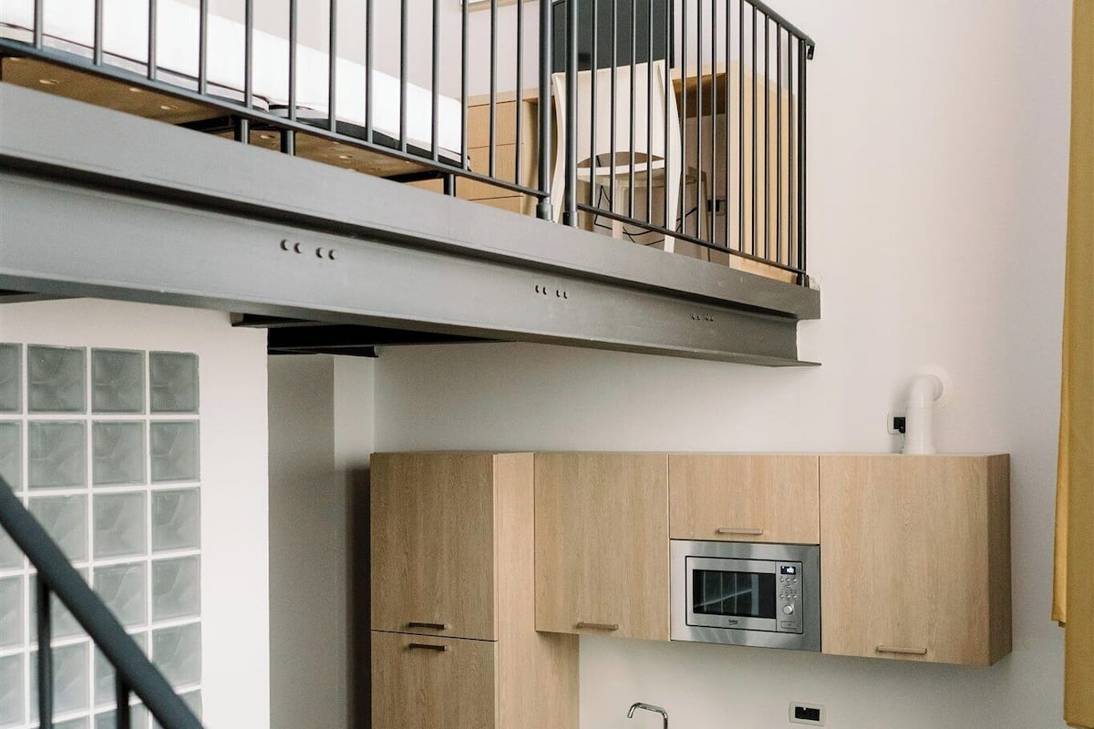 Un apartamento moderno con cocina, comedor y sala de estar con sofá verde.
