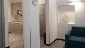 A modern living room with a teal sofa, a wall-mounted clock, and a decorative metal piece. - Hotel Carlton (Ferrara)