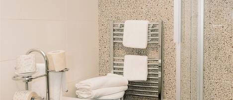 A modern bathroom with a freestanding toilet, a sink, and a glass-enclosed shower.