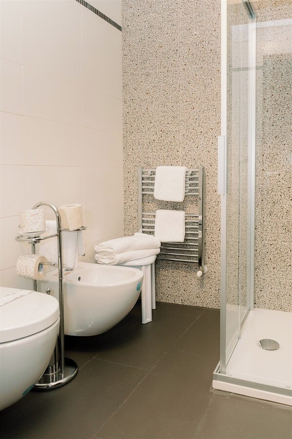 A modern bathroom with a freestanding toilet, a sink, and a glass-enclosed shower.