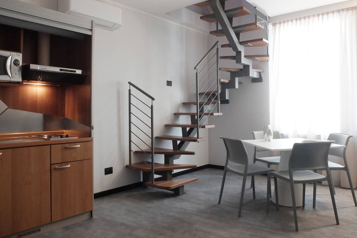 Una cocina moderna con armarios de madera, microondas integrado y campana extractora de acero inoxidable.