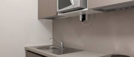 A kitchen with a built-in microwave, a sink, and a stovetop.