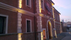 A red brick building with white trim and a large arched doorway. - Hotel Carlton (Ferrara)