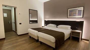 Habitación de hotel con cama doble, dos mesitas de noche, un tocador, un espejo grande y un cuadro en la pared.