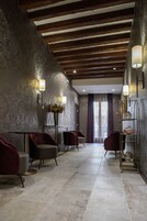 Um saguão de hotel com papel de parede estampado, vigas de madeira no teto e assentos modernos.