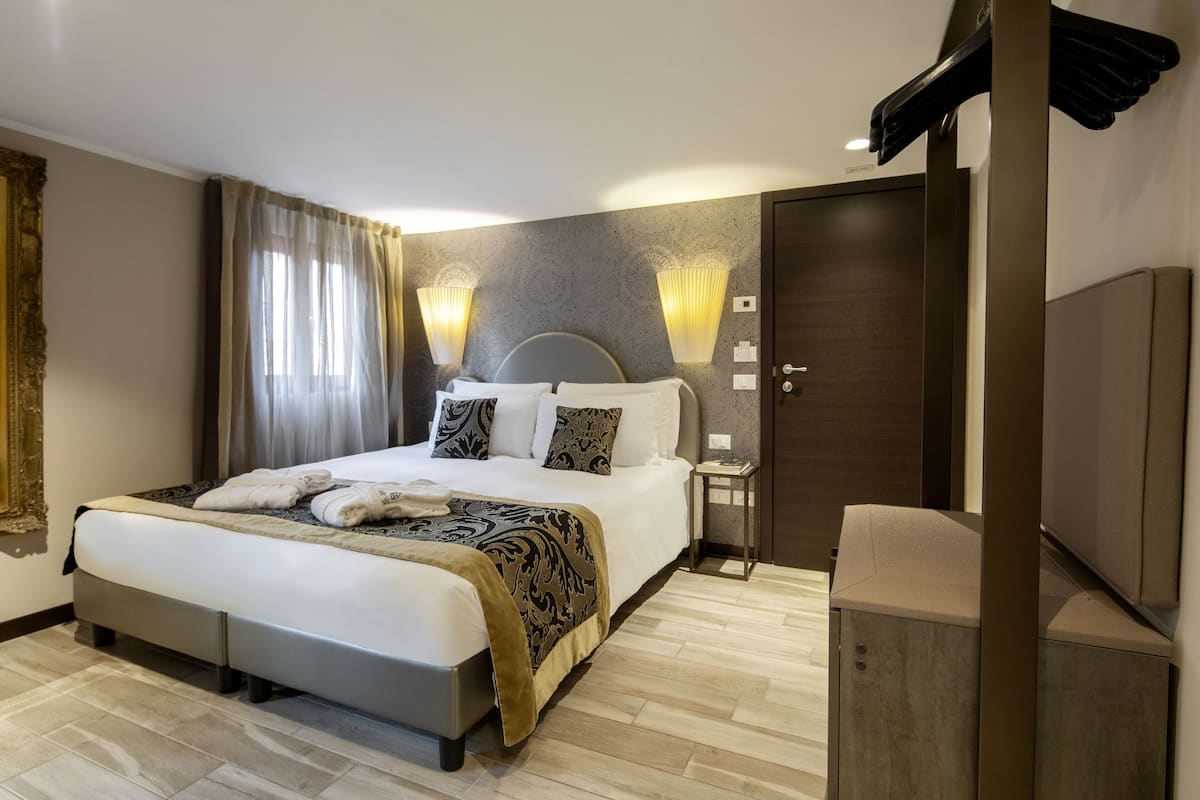 Een moderne hotelkamer met een groot bed, nachtkastjes, een kledingkast en wandlampen.