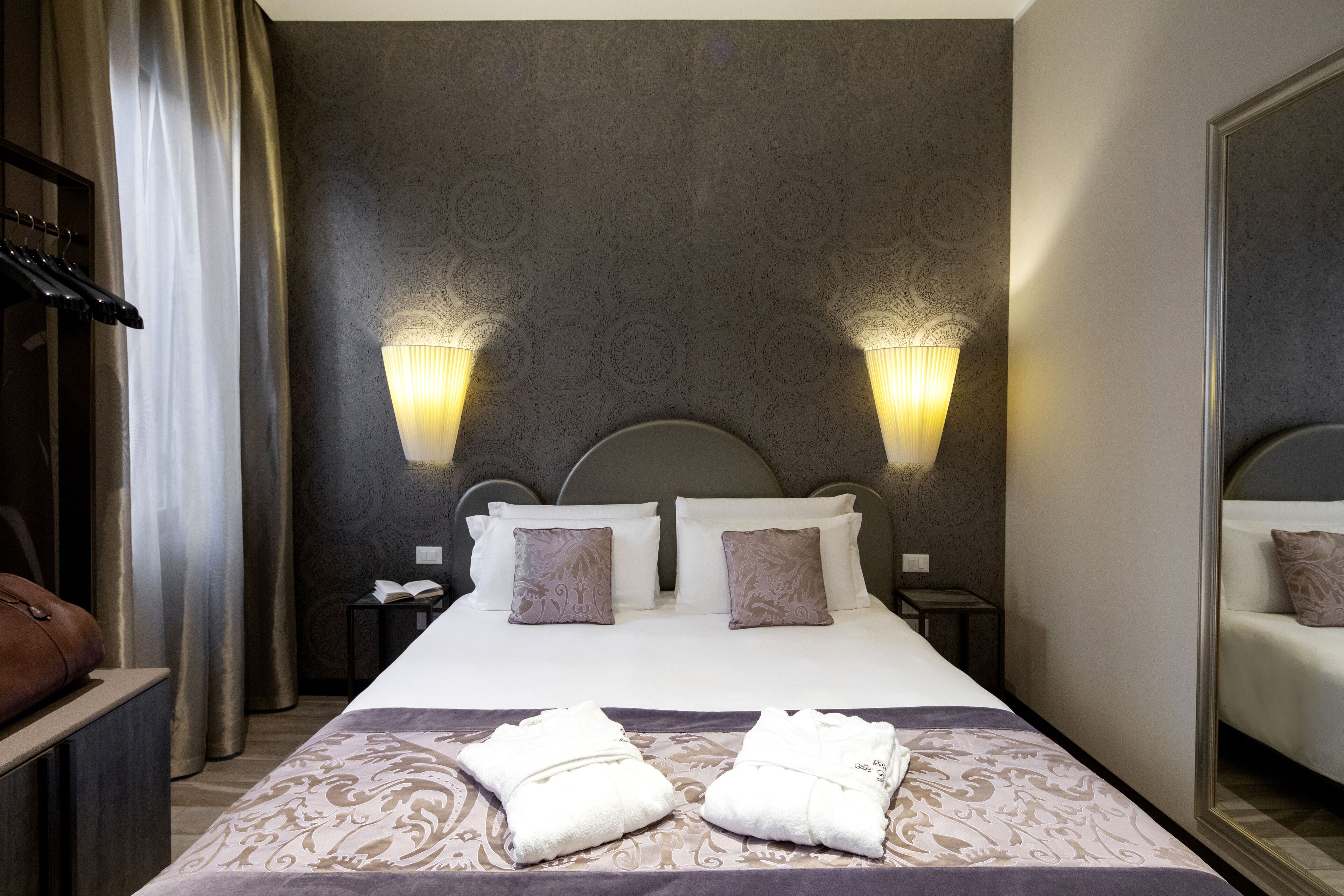 Une chambre d’hôtel avec un grand lit, deux lampes de chevet, une table de chevet avec un téléphone et un miroir au mur.