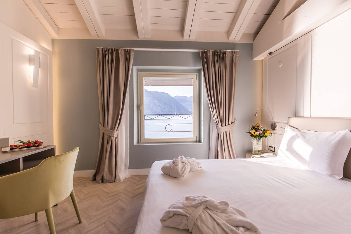 Une chambre d’hôtel avec un lit, un bureau, une chaise et une fenêtre avec des rideaux.
