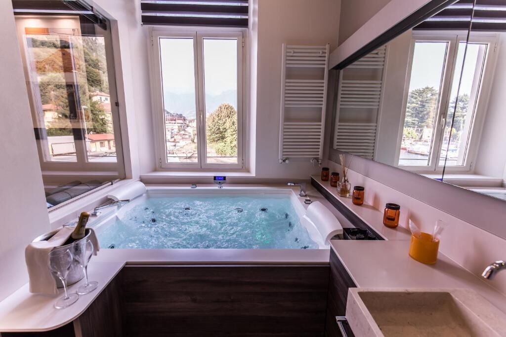 A bathroom with a bathtub, a window with a view, a sink, and a mirror.
