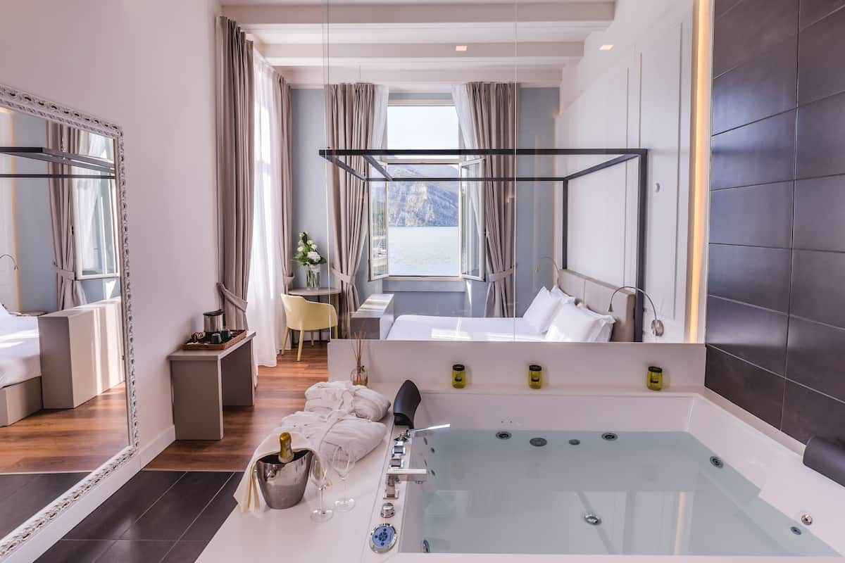 Une chambre d’hôtel moderne dotée d’une grande fenêtre, d’une baignoire et d’un coin salon offrant une vue sur les montagnes.