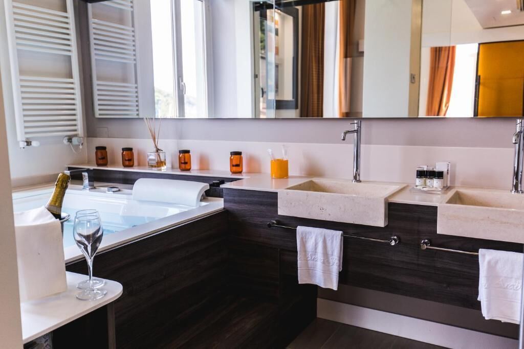 A modern bathroom with a large bathtub, two sinks, and a vanity area.