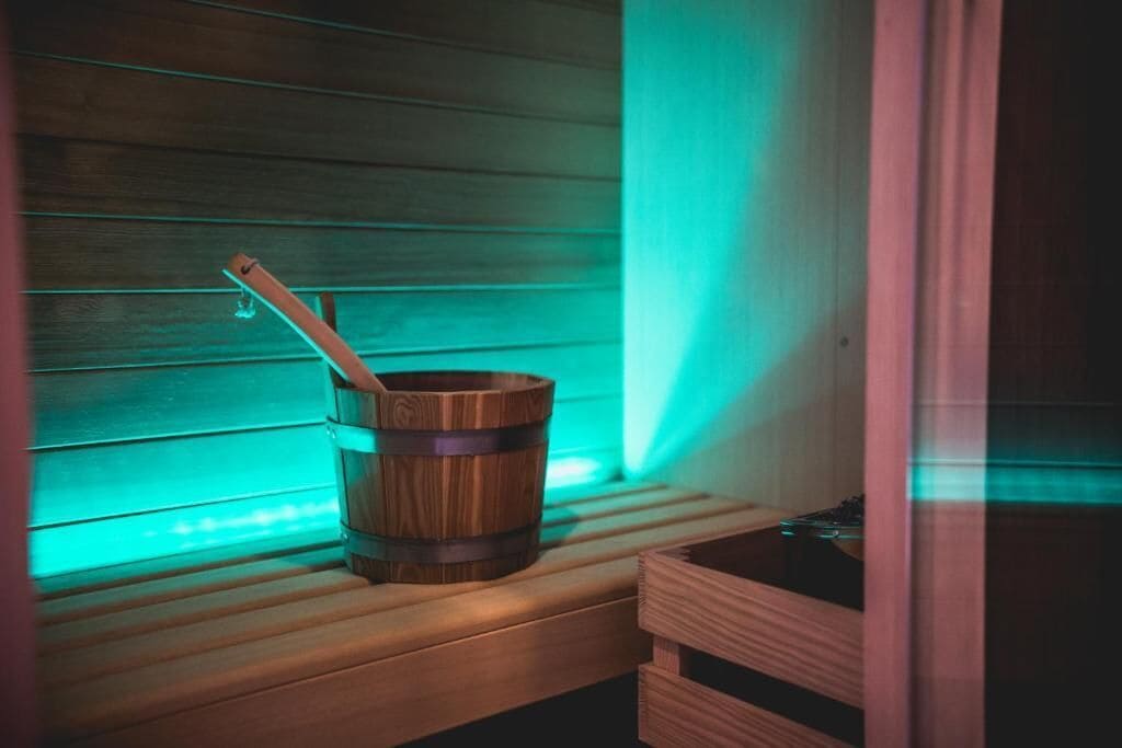 A sauna with wooden benches and a wooden bucket with a ladle.