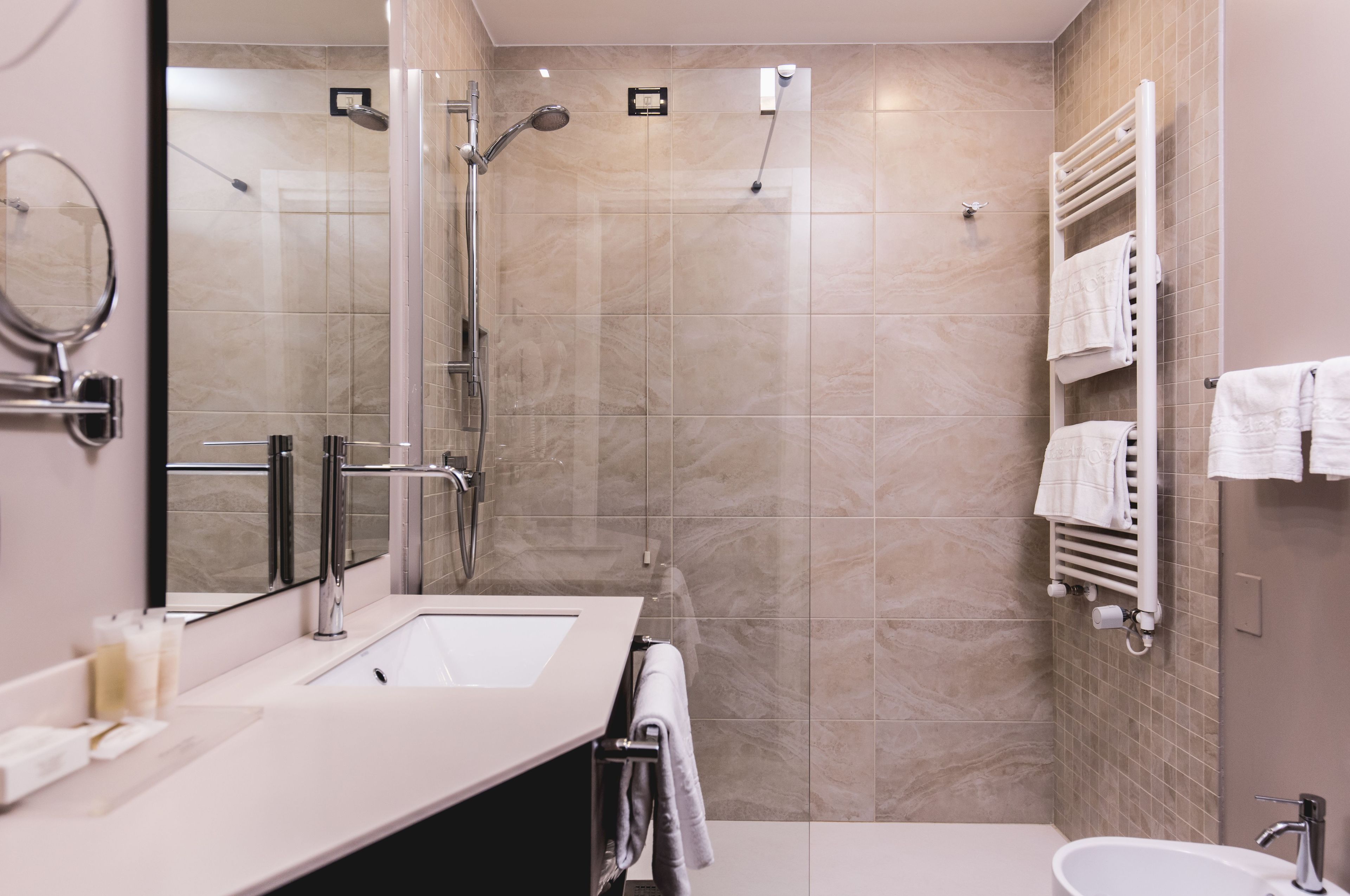 A modern bathroom with a glass-enclosed shower, a large mirror, and a white sink.