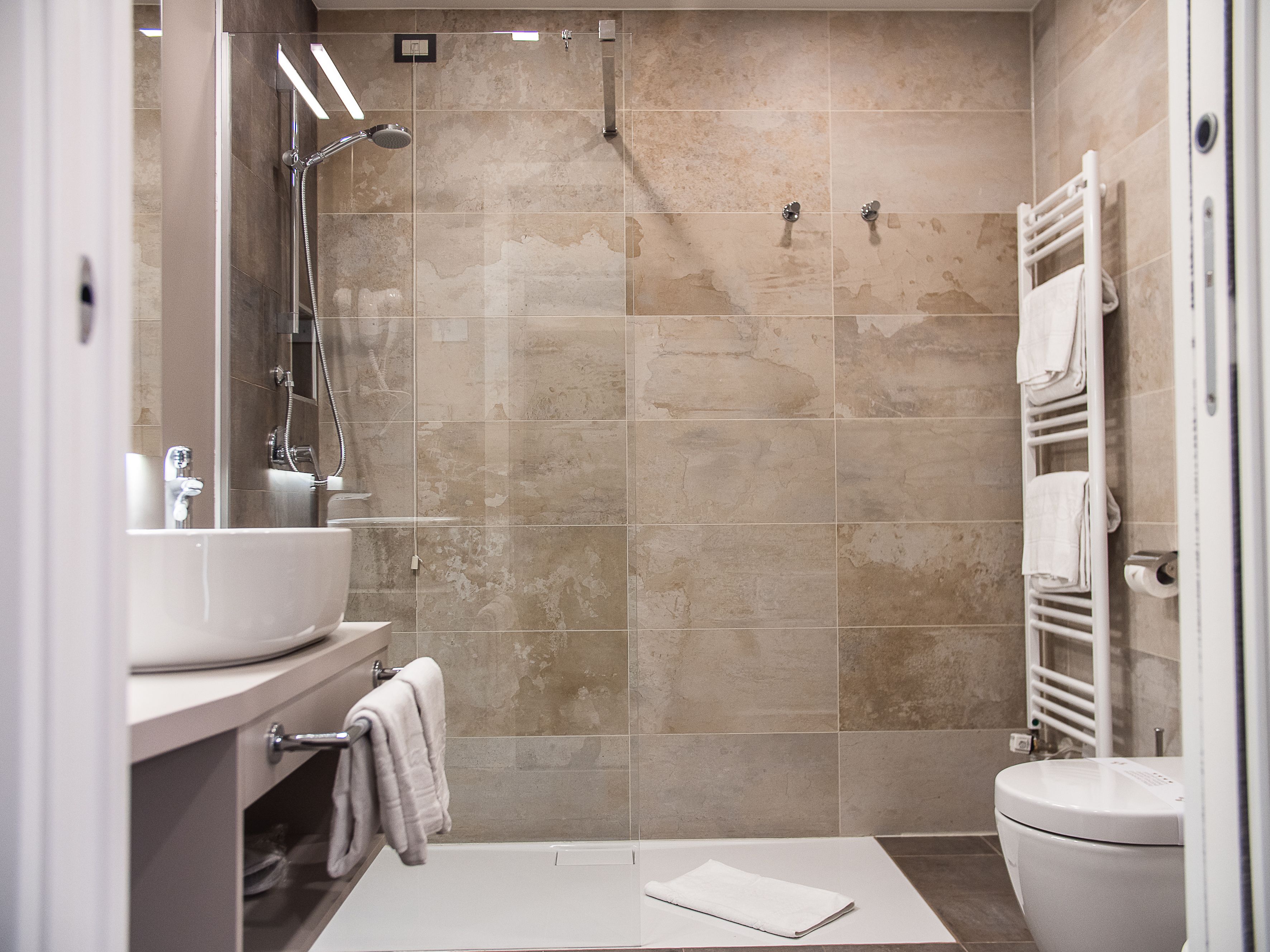 A modern bathroom with a shower, sink, and toilet.