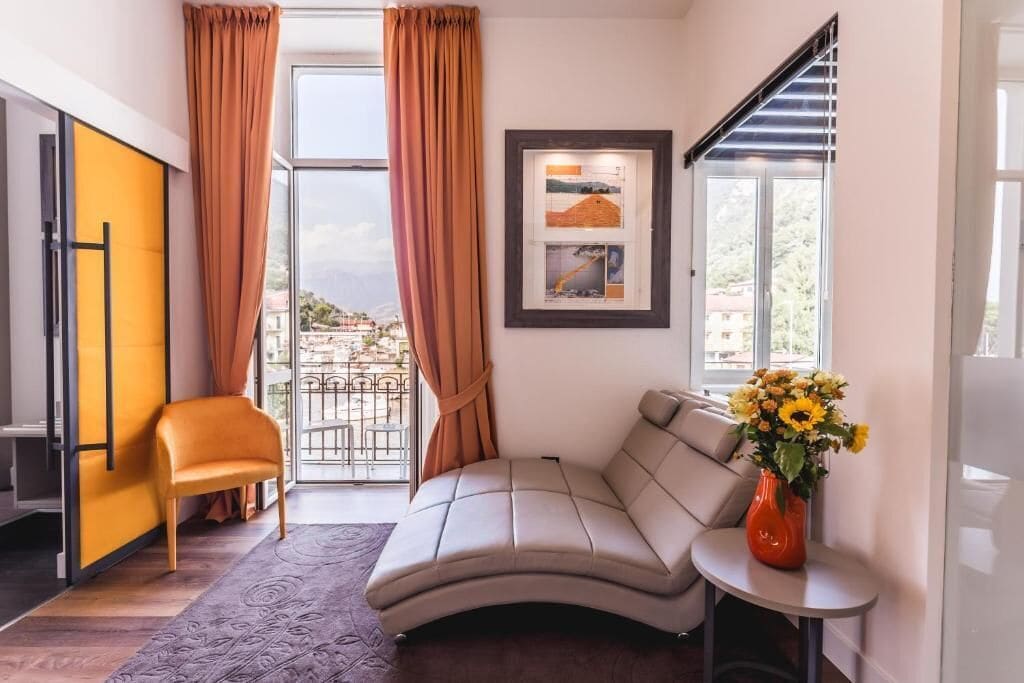 A modern room with a sofa, a chair, a small table with a vase, and a framed picture on the wall.