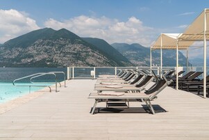 Un espace aménagé au bord de la piscine, avec des chaises longues, une piscine et une vue sur les montagnes.