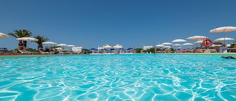 Una piscina al aire libre, sombrillas, tumbonas