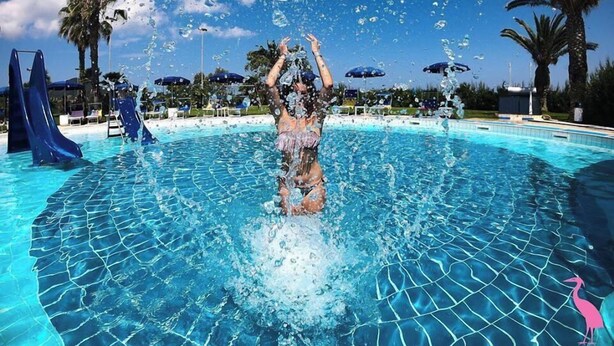 Iemand die in een zwembad speelt, met opspattend water.