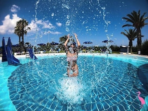 Une personne qui joue dans une piscine et qui éclabousse l’eau.