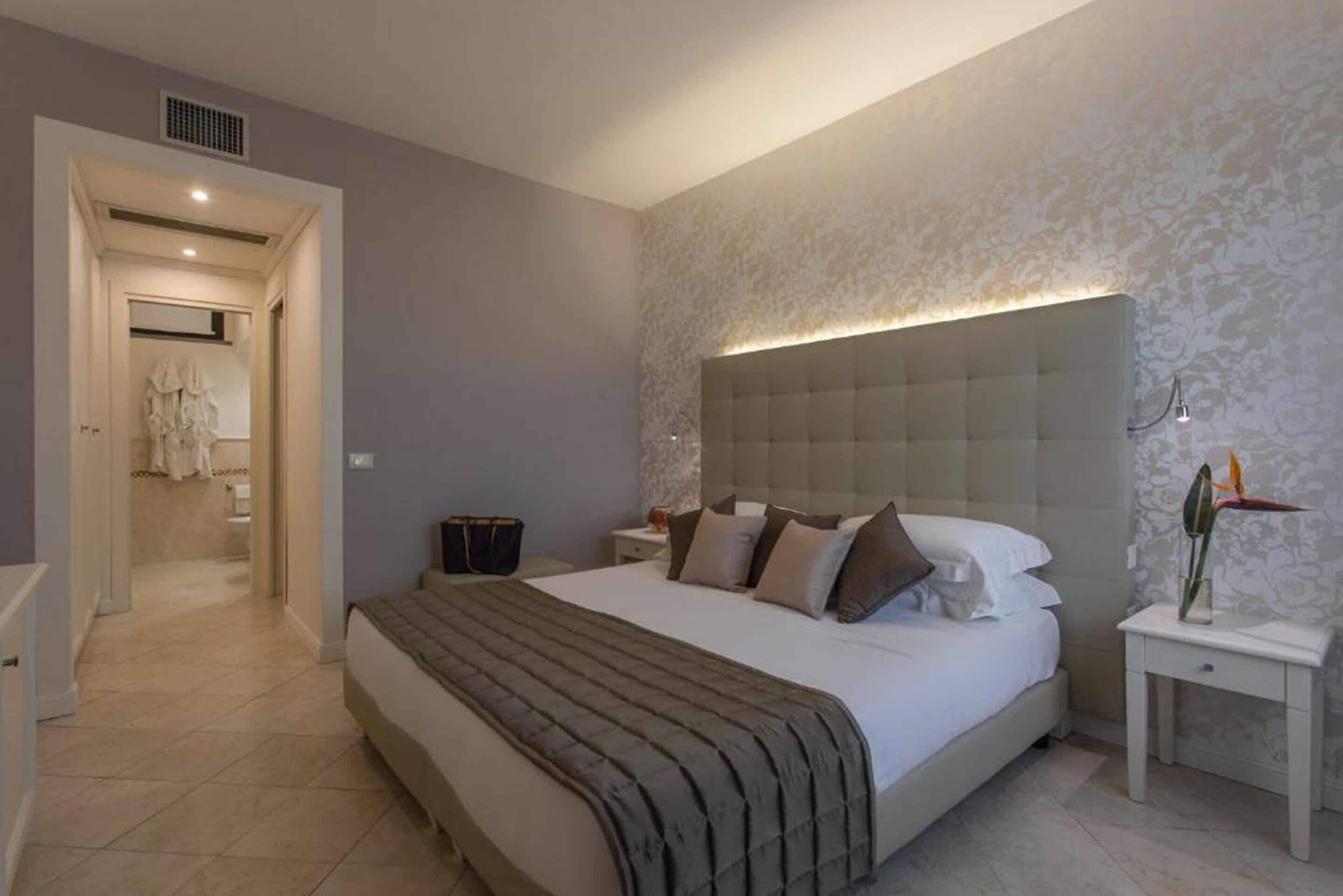 A modern bedroom with a large bed, a nightstand, and a wall-mounted light.