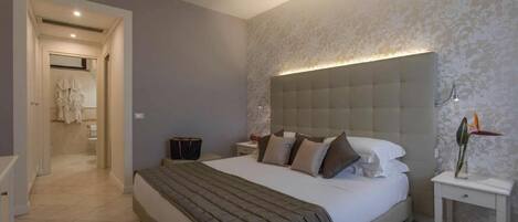 A modern bedroom with a large bed, a nightstand, and a wall-mounted light.