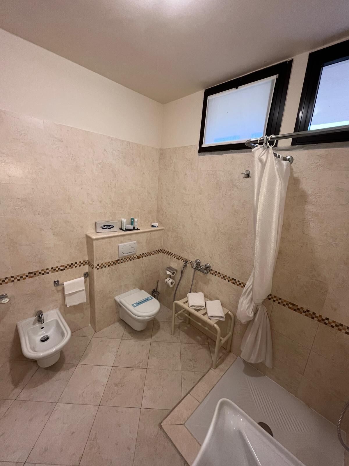 A small bathroom with a toilet, bidet, sink, and shower.