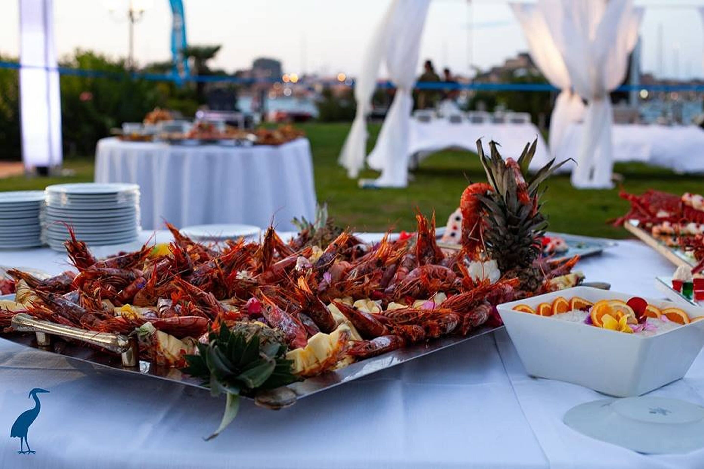 Un buffet de fruits de mer avec des crevettes et de l’ananas, disposé sur une table entourée de nappes blanches et surmonté d’une structure en forme de dais, également blanche.