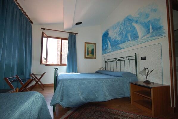 Quarto com cama, uma cadeira, mesa de cabeceira, quadro e janela com cortinas.