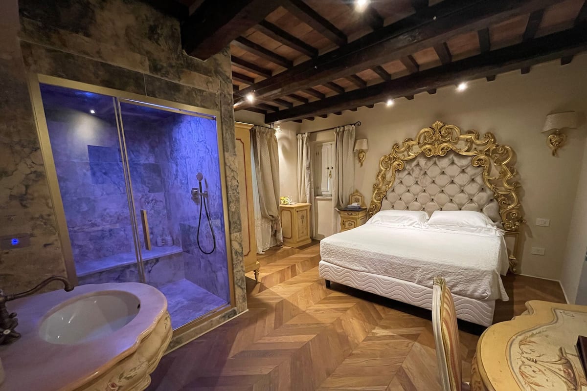 A bedroom with a large bed, a bathtub, and a stone wall.