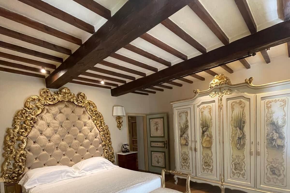 A bedroom with a large bed, ornate headboard, and a classic design.