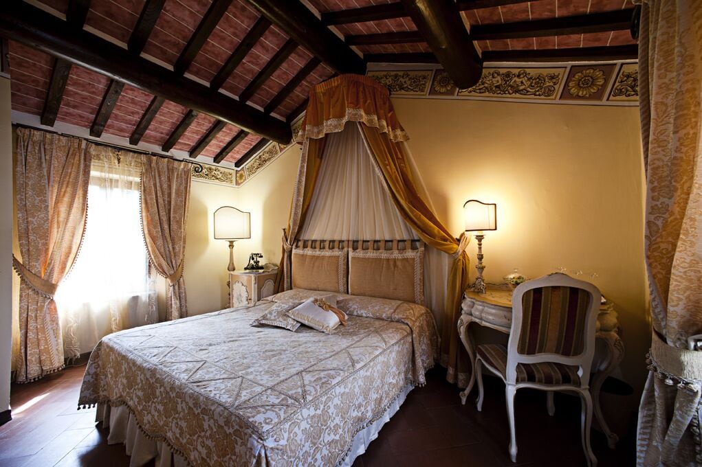 A bedroom with a large bed, a desk, and two chairs.