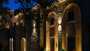 A historic stone building with arched doorways and a courtyard at twilight.