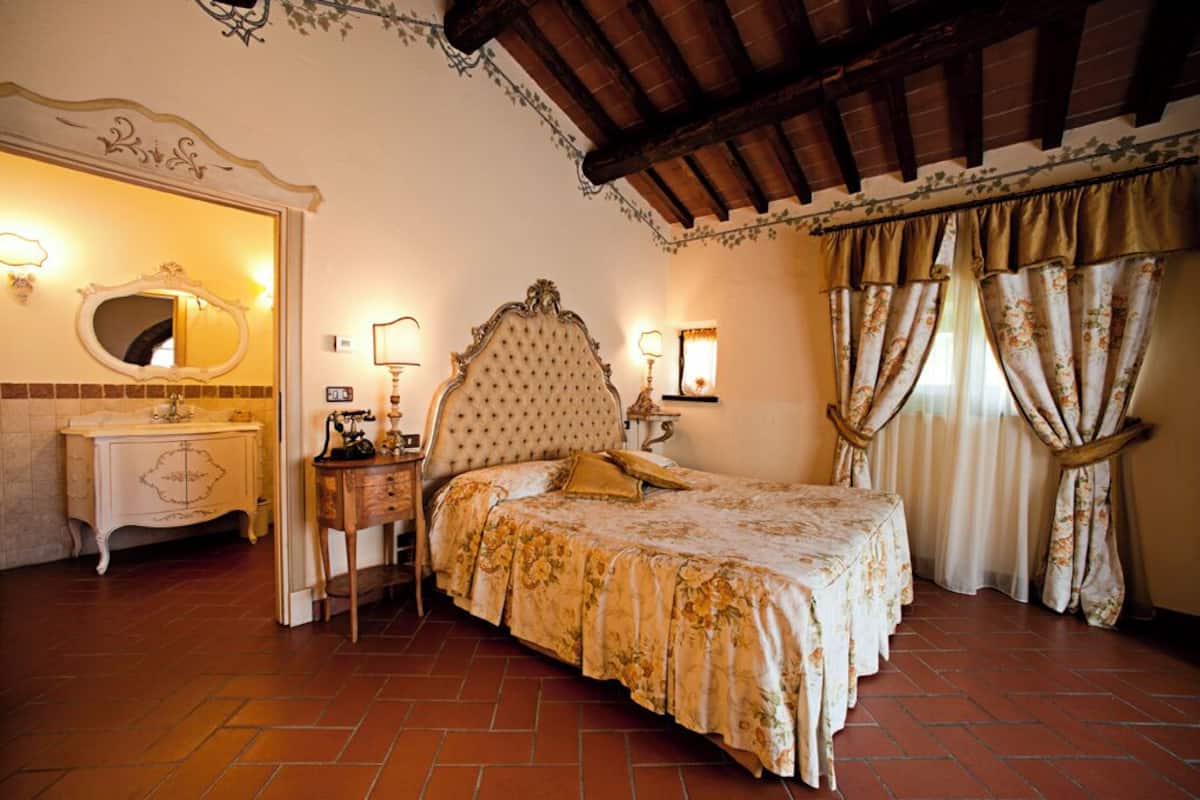 A bedroom with a large bed, a vanity with a mirror, and a nightstand.