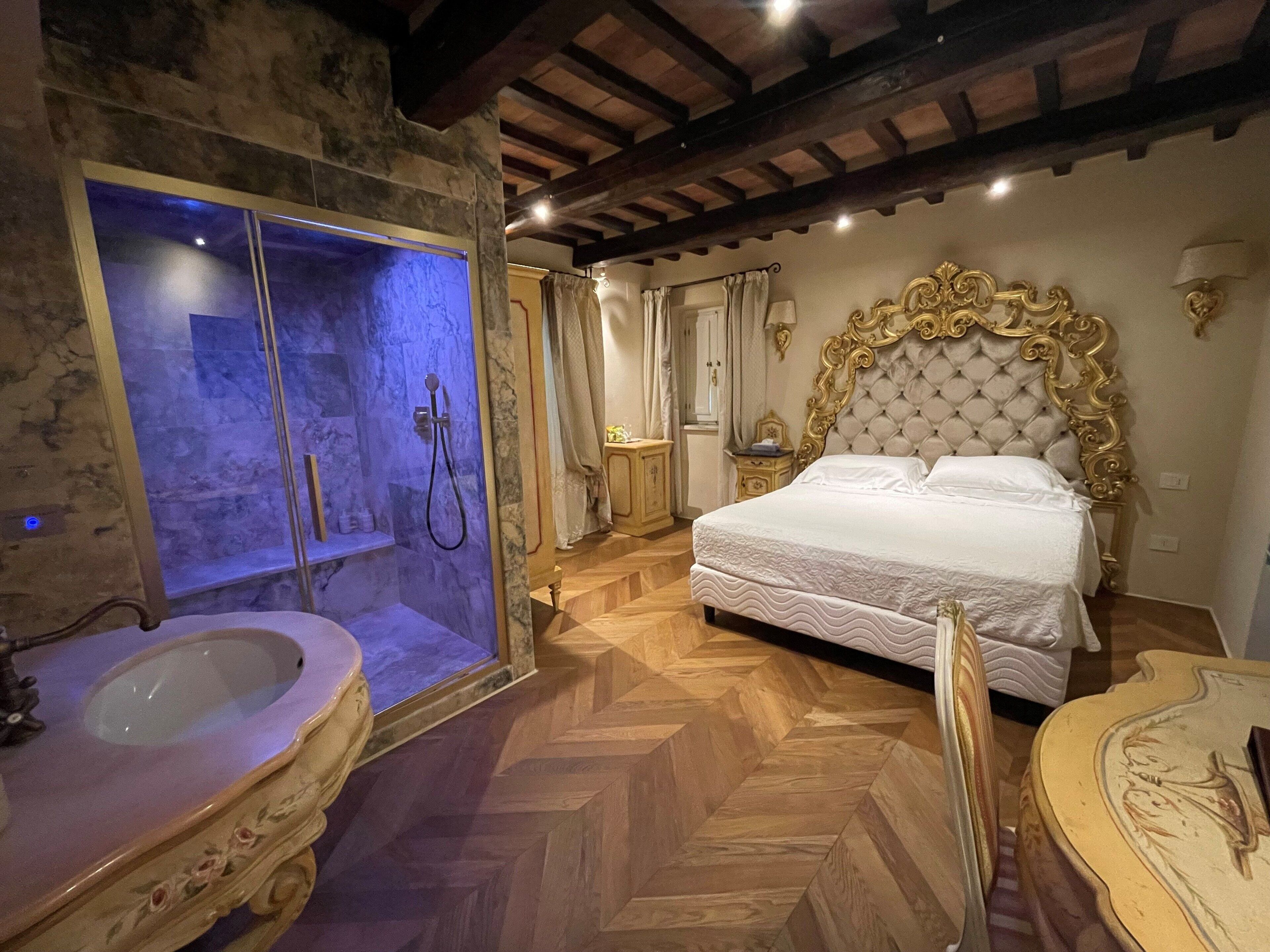 Une chambre avec un grand lit, une salle de bain avec une baignoire et un plancher en bois.