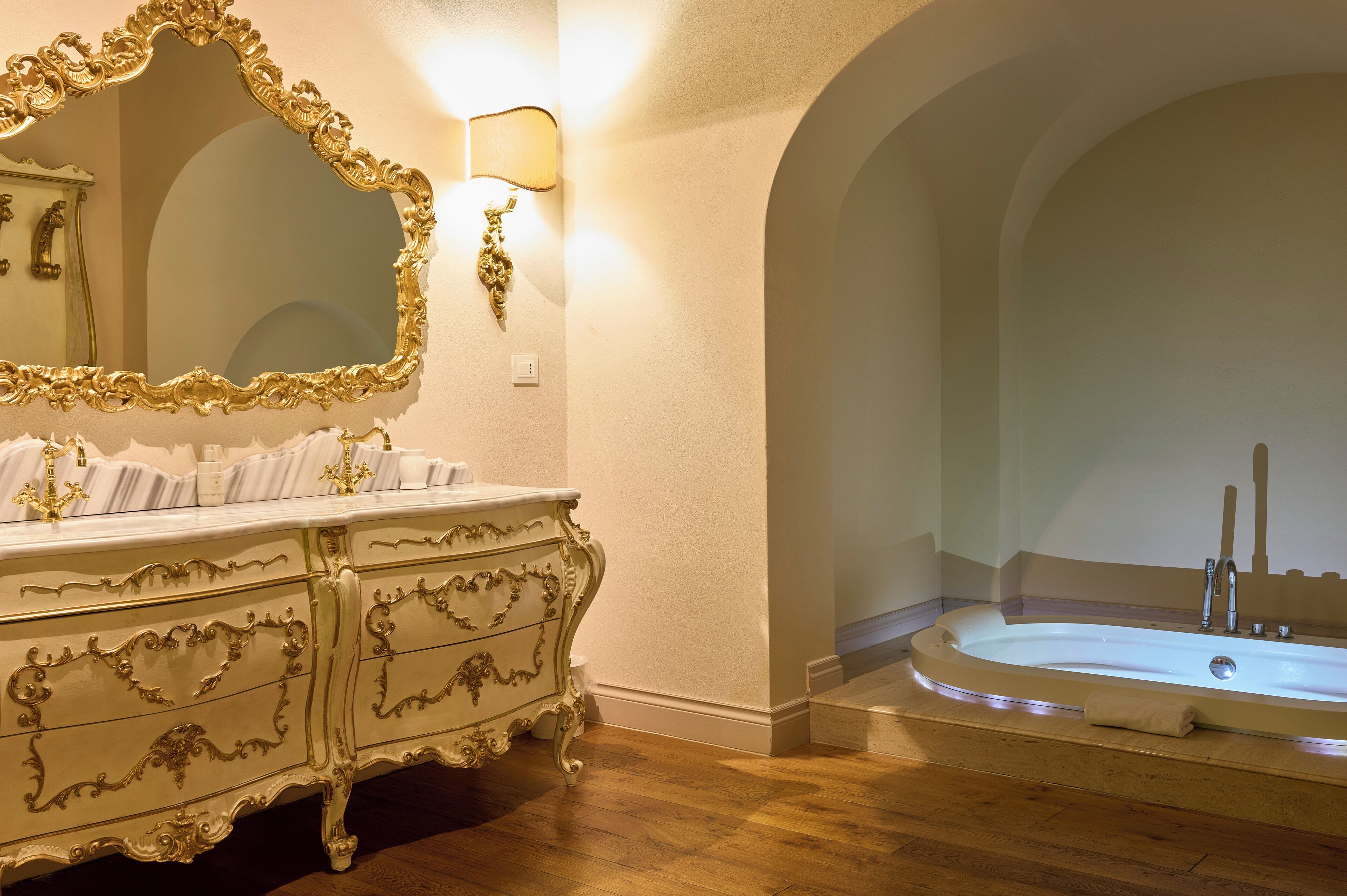A luxurious bathroom with an ornate vanity, a large mirror, and a freestanding bathtub.