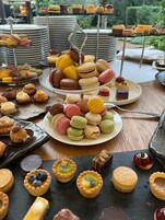 Una variedad de postres sobre una mesa, incluyendo macarons, tartaletas y pasteles pequeños.