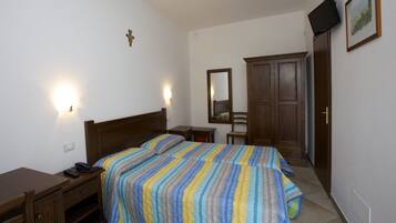 Ein Schlafzimmer mit zwei Betten, einem Holztisch, einem Stuhl, einem Kleiderschrank und einem an der Wand montierten Fernseher.