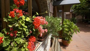 A brick building with a wooden balcony, potted plants, and a tiled patio. - Da Angelo (Assisi)