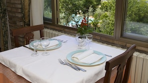 A dining table set with plates, glasses, and cutlery, with a view of greenery and a building through the window. - Da Angelo (Assisi)