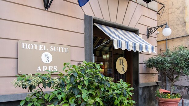 A hotel entrance with a sign reading "HOTEL SUITE ARES" and a striped awning. - Hotel Suite Ares (Naples)
