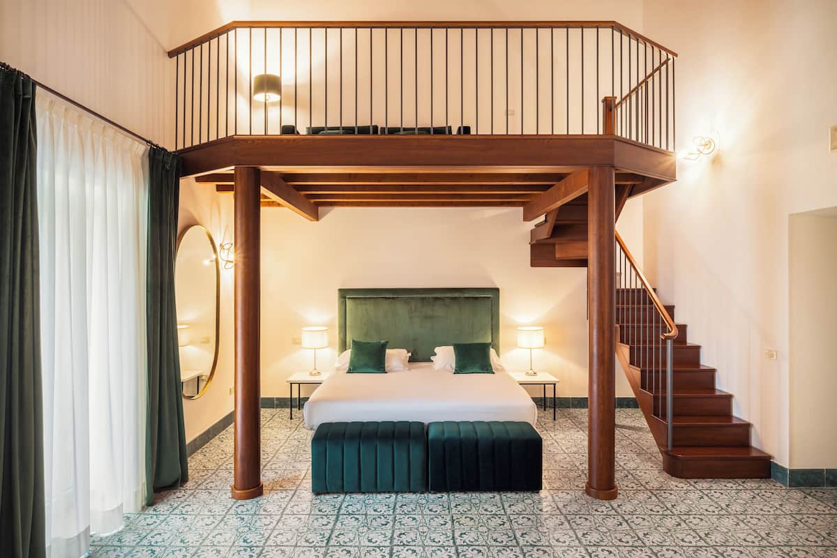 Un dormitorio con una cama grande, un balcón de madera y una escalera.