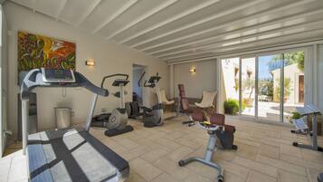 Une salle de sport équipée de tapis de course, de vélos d’appartement et d’appareils de musculation.