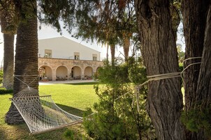 A hammock between trees, a stone building with arches, and a clear sky.