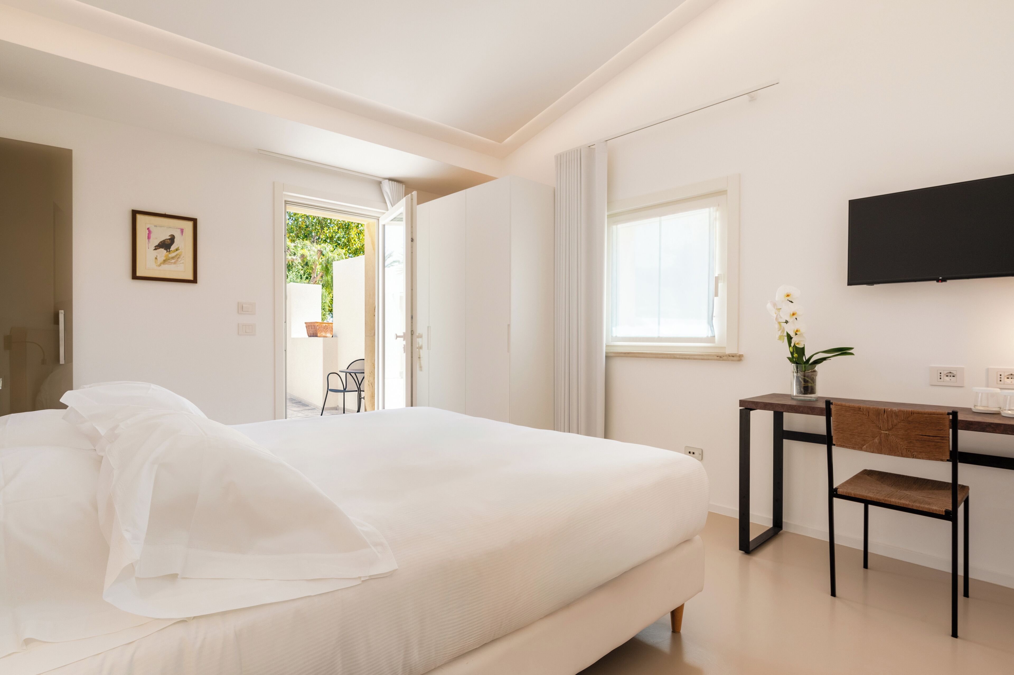 Une chambre à coucher avec un lit, un bureau, une chaise, une télévision et une fenêtre.