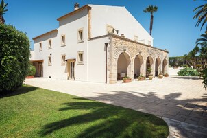 A white building with stone arches and a paved courtyard.