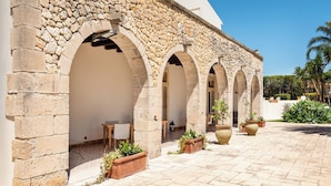 Un edificio de piedra con paseos en arco y zonas de estar al aire libre.