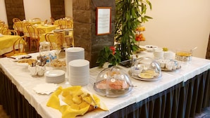 A buffet setup with various food items and utensils, including plates, bowls, and a glass dome covering a dish. - Hotel Vittoria & Orlandini (Genoa)