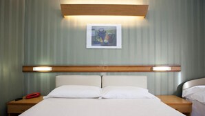 A hotel room with a bed, two bedside tables, a nightstand, a red telephone, and a framed picture on the wall. - Hotel Vittoria & Orlandini (Genoa)