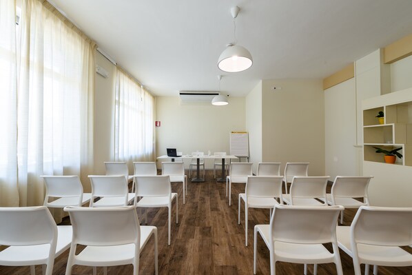 A conference room with white chairs, a whiteboard, and a laptop on a table. - Hotel Regent (Pescara)